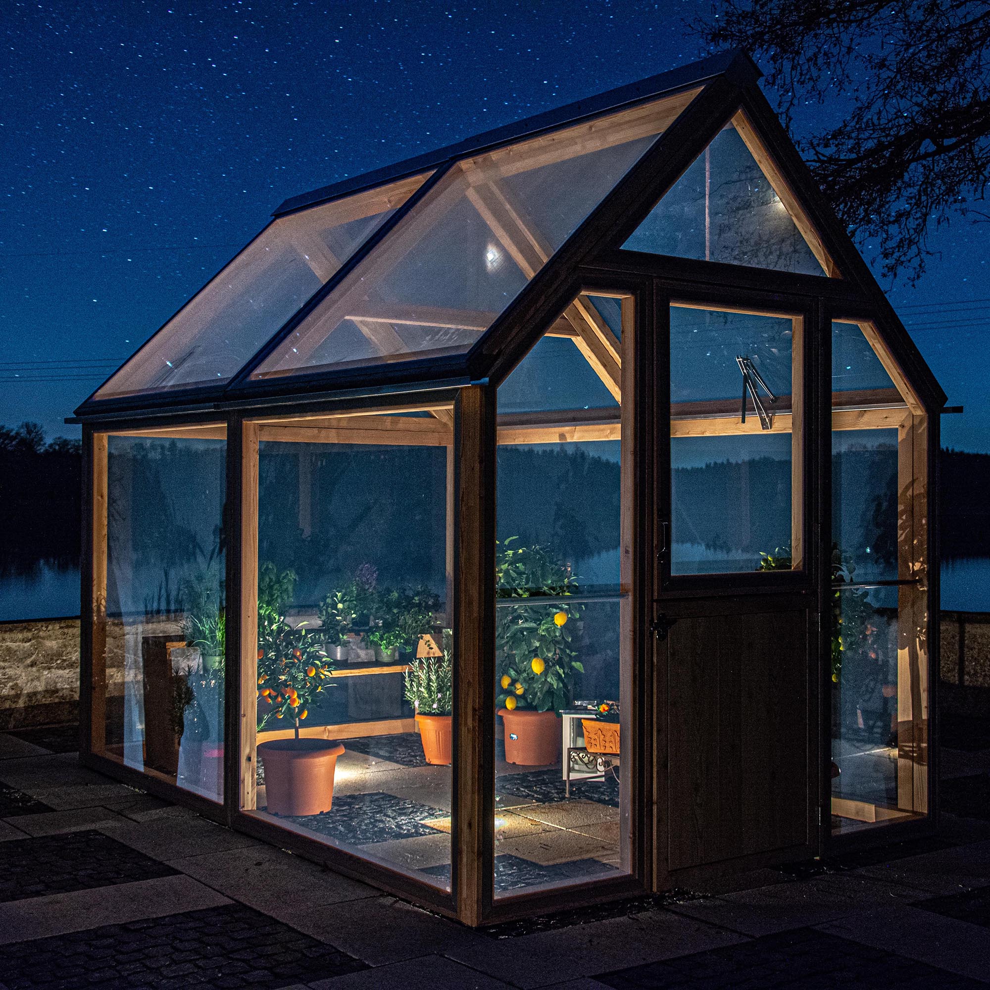 Ein Serra II am Abend, innen warm beleuchtet, mit Pflanzen in Töpfen